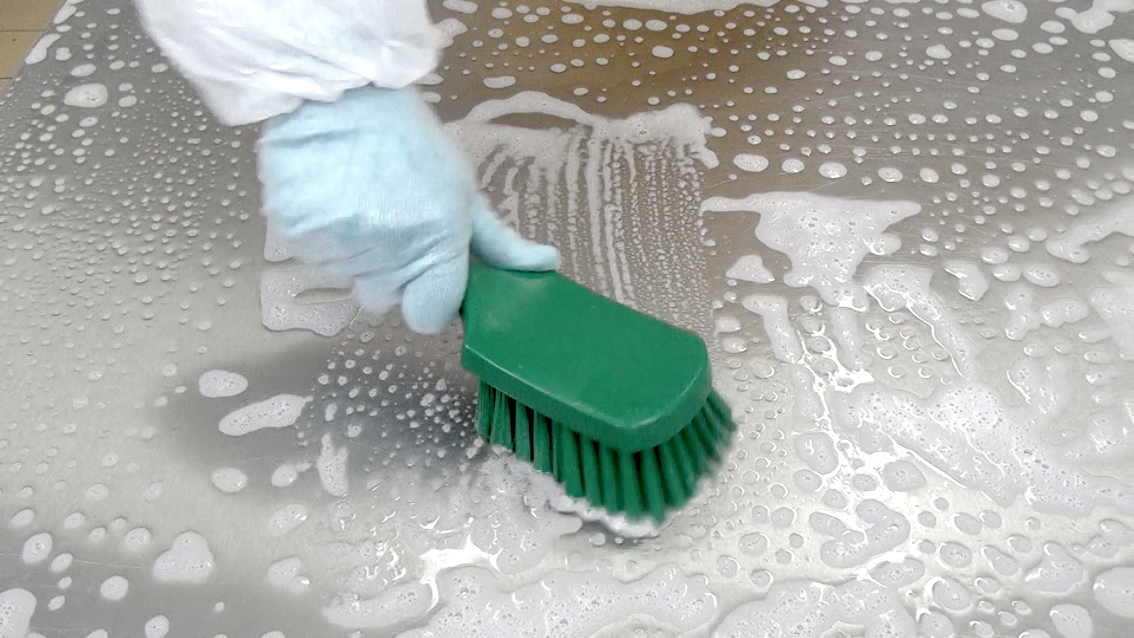 Sanitização fácil uma pessoa limpando uma superfície com uma escova verde