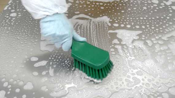 Easy Sanitization eine Person, die eine Oberfläche mit einer grünen Bürste reinigt